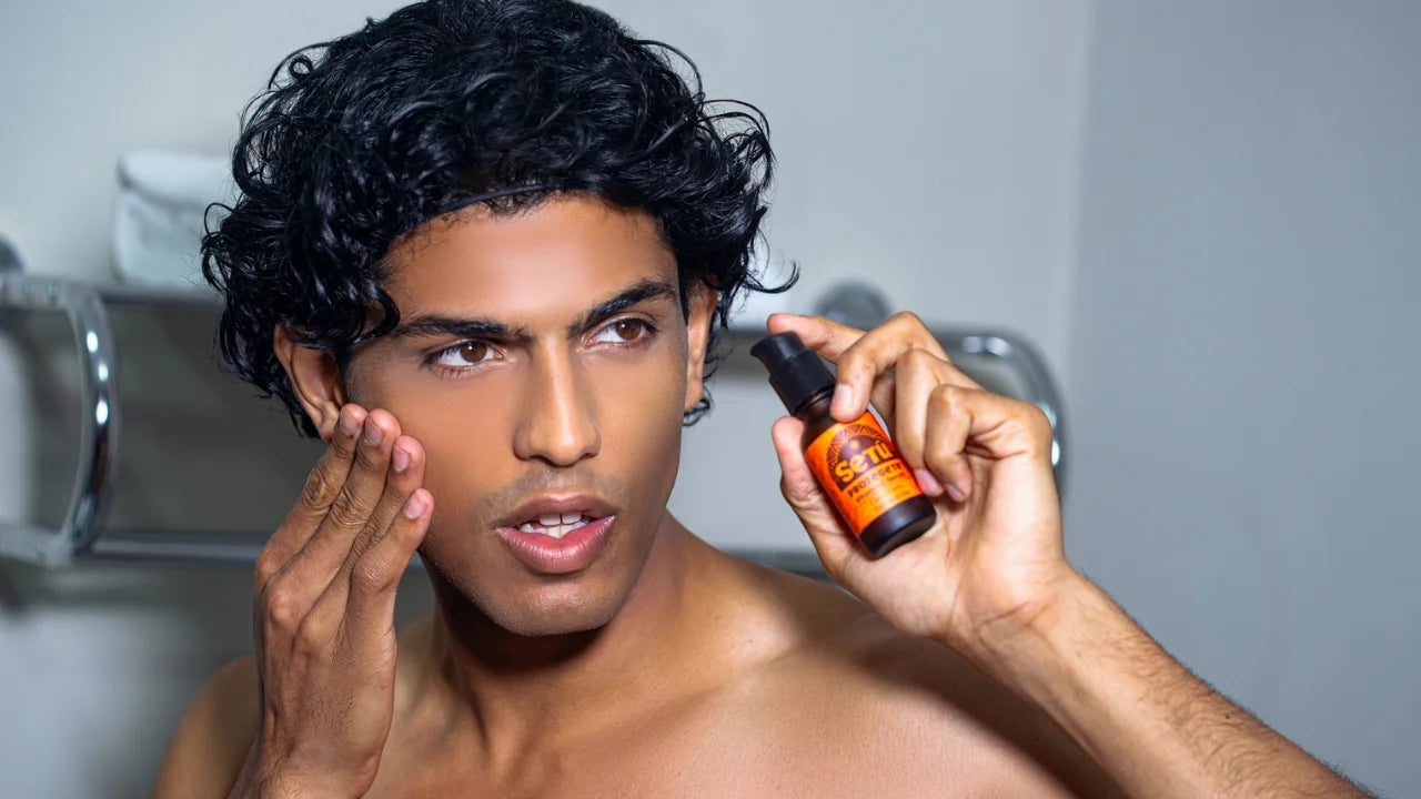 A man with dark curly hair applies a setu skincare serum