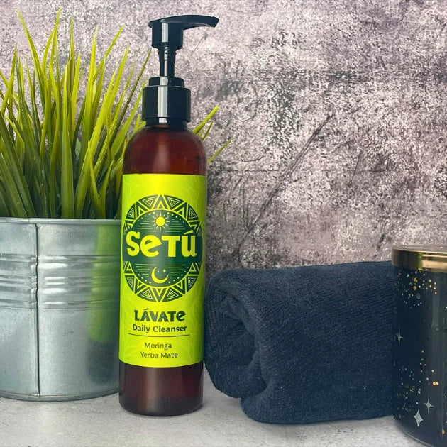Setu Lavate Daily Cleanser bottle with green label on a textured surface with plant and towel.
