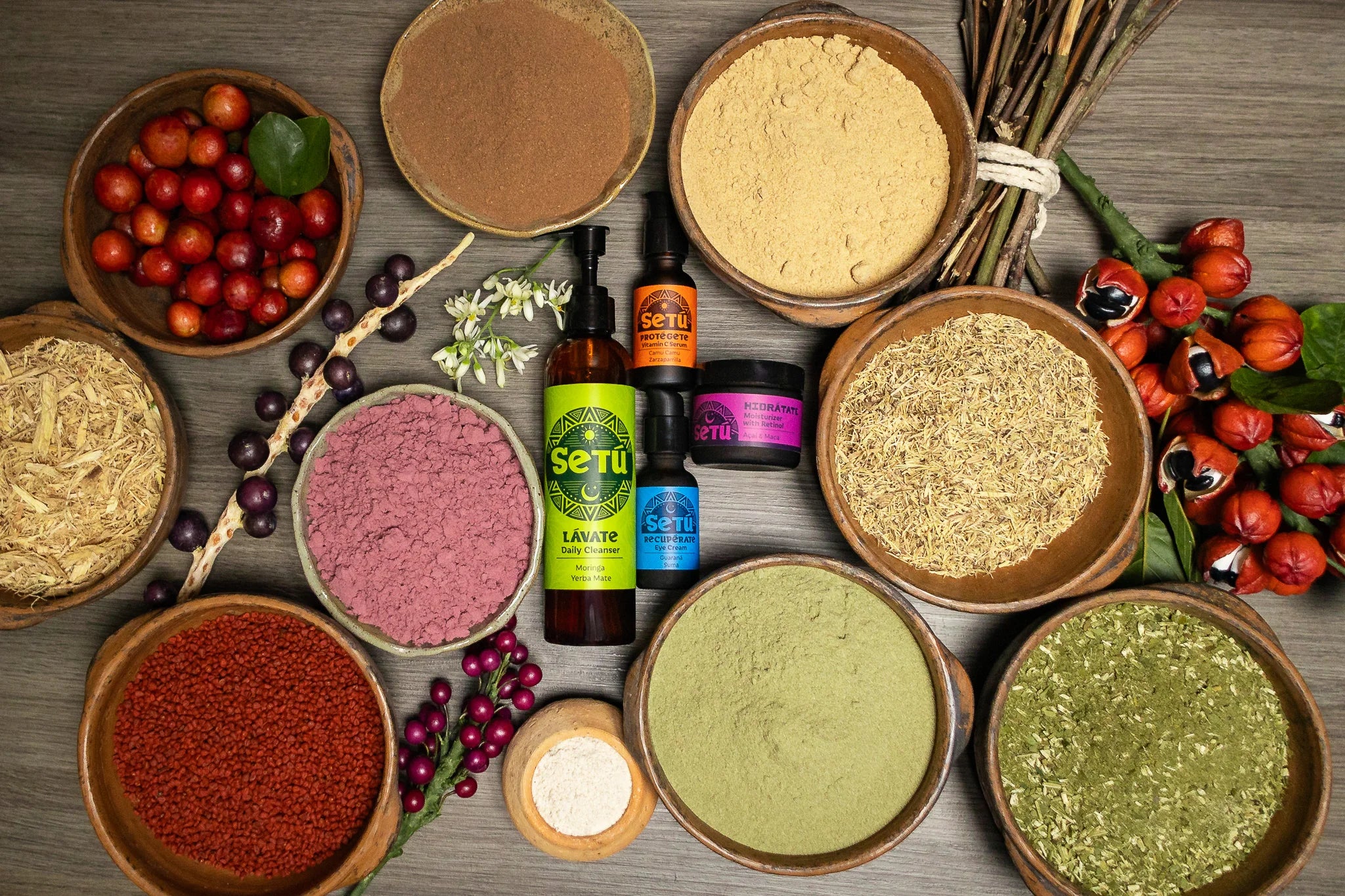 Assorted latin ingredients in bowls with bottles of setu skincare for men and fruits on a wooden surface