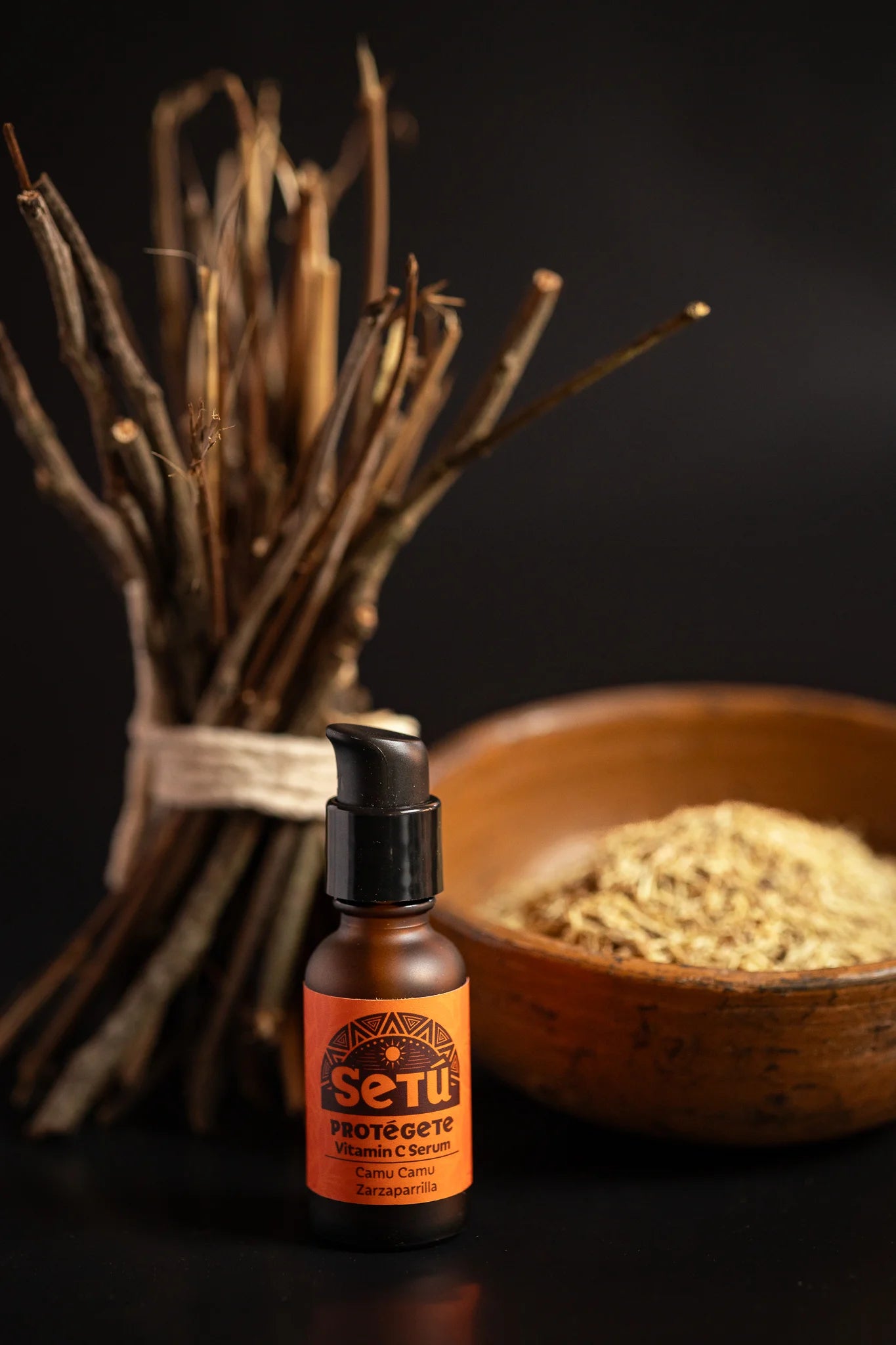SETU PROTEGETE with an orange label, placed in front of a bundle of sarsaparilla and a wooden bowl filled with loose powder on a dark background.